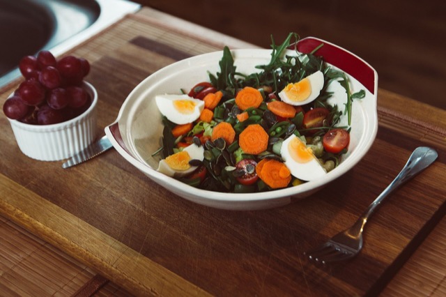 A salad with arugula, eggs, carrot and tomato
